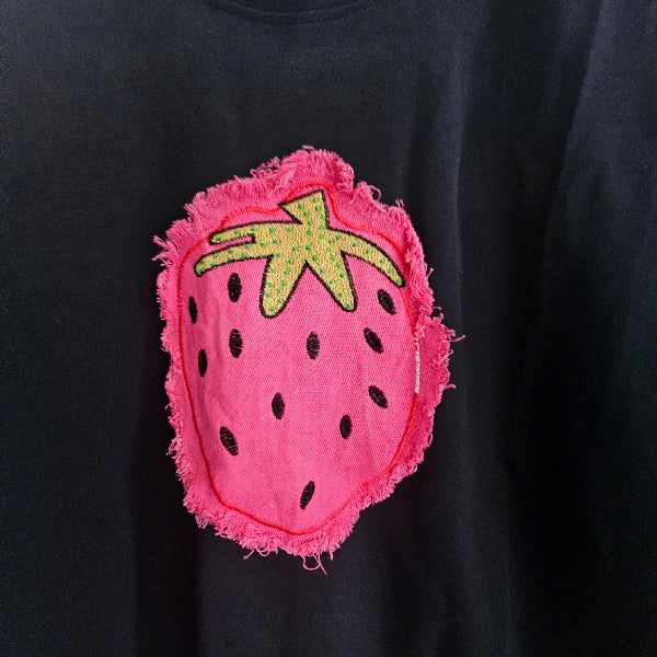 Pink strawberry-shaped patch with green leaves on a black background