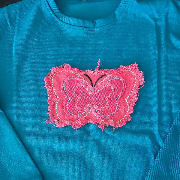 Blue shirt with a pink embroidered heart design on a plain background