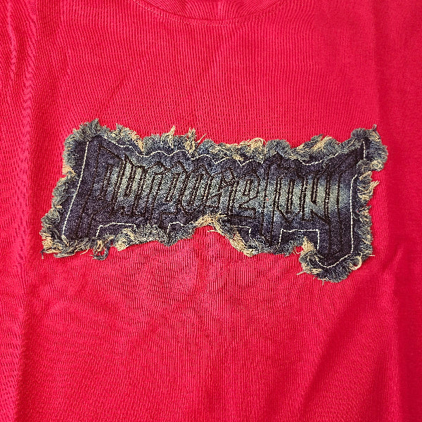 Red t-shirt with a large black patch featuring text and graphics on a red background