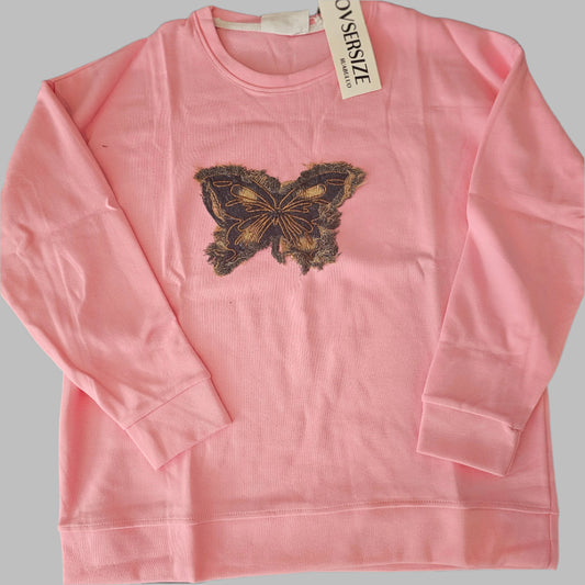 Pink t-shirt with a butterfly design and 'Oversize' label on a black surface.